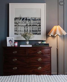 a bedroom with a dresser, lamp and pictures on the wall