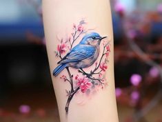 a blue bird on a branch with pink flowers