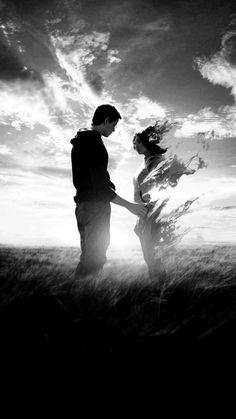 black and white photograph of two people standing in a field with the sun behind them