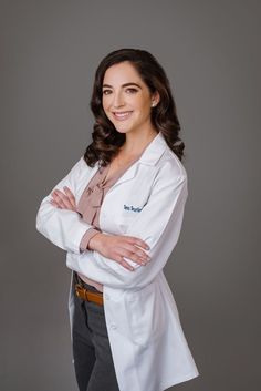 a woman in a white lab coat posing for the camera with her arms crossed and smiling