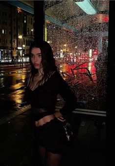 a woman standing in front of a window covered in rain