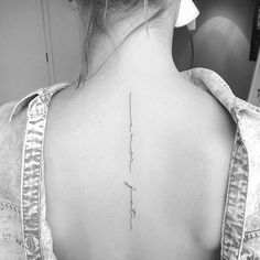 the back of a woman's neck with a cross tattoo on her left shoulder