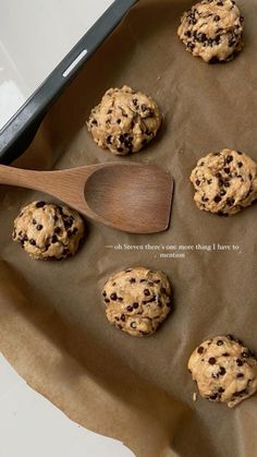 chocolate chip cookies sitting on top of a baking sheet with a wooden spoon next to them