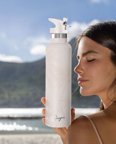 a woman holding a white water bottle in front of her face