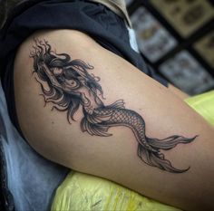 a woman's thigh with a tattoo design on her leg and an image of a fish