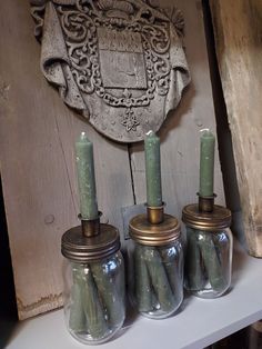 three jars filled with candles sitting on top of a shelf