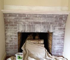 a fire place with a blanket on top of it and two cans of paint next to it