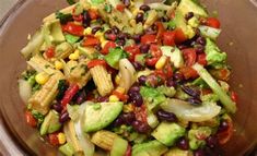 a salad with corn, black beans, avocado and tomatoes in a bowl