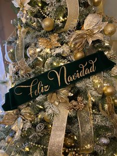 a christmas tree decorated with gold and green ornaments, ribbon that says feliz navidad