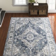 a blue and white area rug in a living room with hardwood floors, windows, and furniture