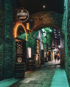 an alley way with brick walls and green lights