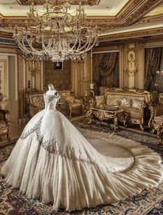 a wedding dress is displayed in the middle of a room with gold furniture and chandelier