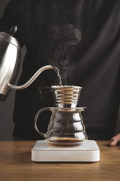 a person pours coffee into a glass pot