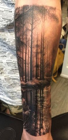 a man's arm with trees and water on it