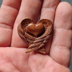 a heart shaped brooch sitting in someone's hand