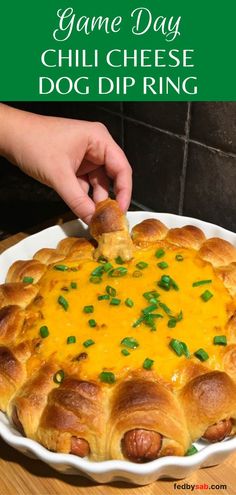 a person dipping cheese on top of a hot dog ring in a casserole dish