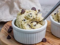 two bowls filled with ice cream on top of a wooden board next to chocolate chips