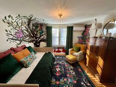 a bedroom decorated in green, white and red with a tree mural on the wall