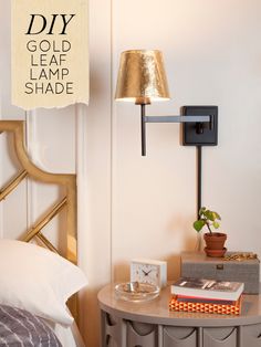 a lamp that is on top of a table next to a bed with a book