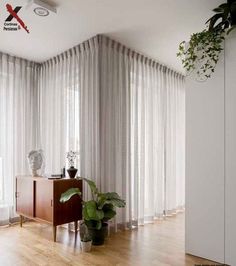 a living room with wooden floors and white curtains on the windowsills, potted plants in front of an open window