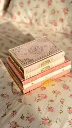 a stack of books sitting on top of a bed covered in floral sheets and pillows