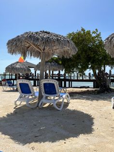 two lawn chairs under an umbrella on the beach