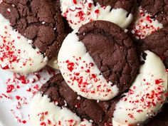 chocolate cookies with white frosting and red sprinkles on a white plate