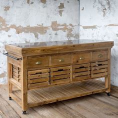 a wooden table with drawers on wheels in front of a brick wall and wood floor