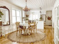 a dining room table with chairs and a chandelier hanging from the ceiling above it