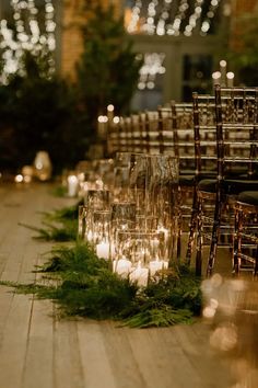 rows of chairs lined up with candles and greenery on the floor in front of them