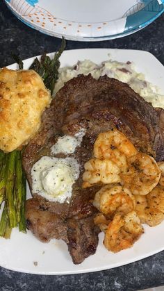 steak, shrimp and asparagus on a white plate