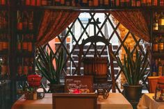 a dining room filled with lots of tables and chairs next to bookshelves full of bottles