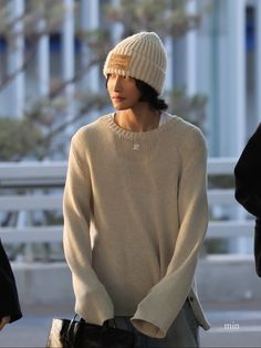 a young man wearing a white hat and sweater is standing in front of some people