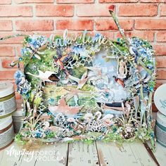 an altered photo frame with birds and flowers on it, sitting next to some paint cans