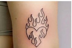 a heart with flames tattoo on the side of a woman's leg, which is black and white