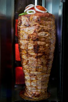 a large piece of meat sitting inside of a oven with onion rings on it's head