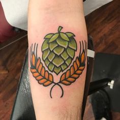 a tattoo on the arm of a man with an orange and green hops design