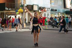 a woman is walking across the street with her arms in the air