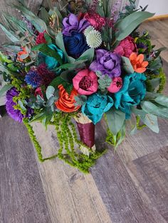 a bouquet of colorful flowers sitting on top of a wooden floor