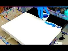 a person in blue gloves is painting a large white box with paint and glue on it