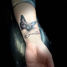 a person with a butterfly tattoo on their wrist that says breathe and the word breathe is written in cursive font