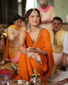 a woman in an orange sari sitting down