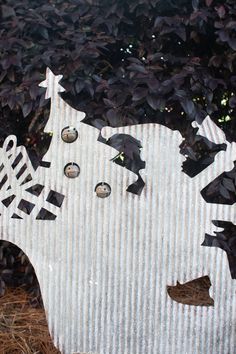 a cardboard cut out of the shape of a cow in front of some bushes and trees