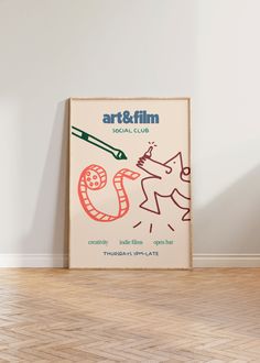 an art and film poster hanging on the wall next to a wooden floor in front of a white wall