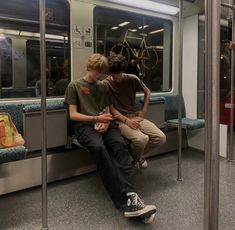 two boys sitting on a subway train looking at their phones