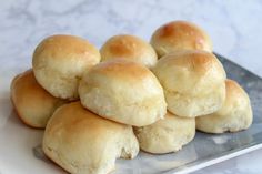 a pile of rolls sitting on top of a white plate next to a glass container