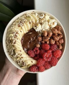 a bowl filled with nuts, raspberries and bananas