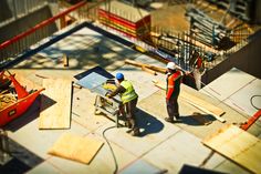 two men working on the roof of a skateboard park while another man looks on