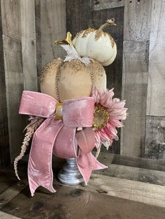 a pink and white pumpkin sitting on top of a metal stand next to a wooden wall