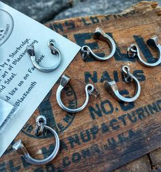 five pairs of metal hooks sitting on top of a wooden box next to a piece of paper